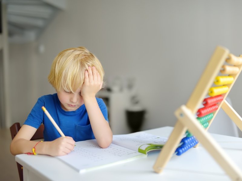 Niña estresada frente a la computadora con dificultad para concentrarse en clase